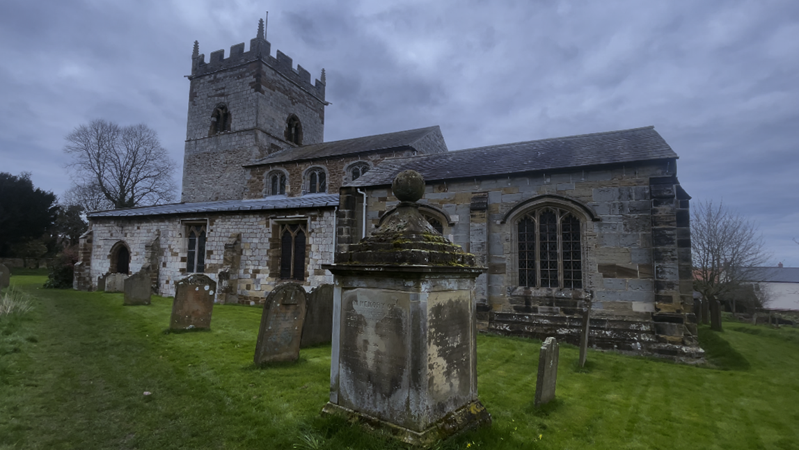 A stone building with a stone tower and a cemetery
Description automatically generated